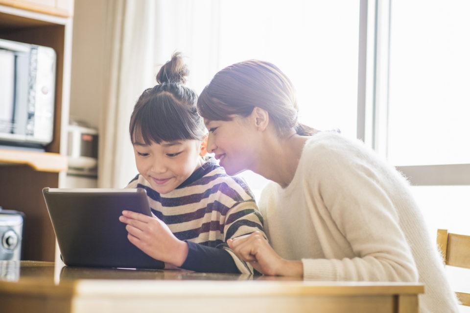 Mother and daughter playing with a digital tablet in room